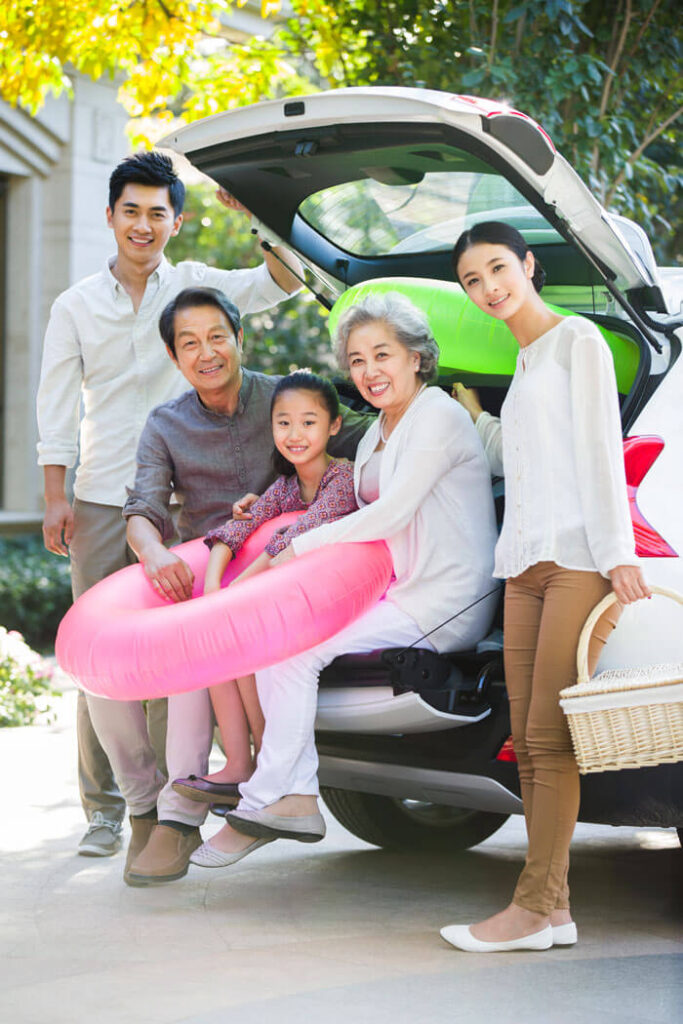 A happy family gathered around their SUV hatchback, protected by AAA insurance policies from Mark Ismail Insurance Agency in Plymouth, MI.
