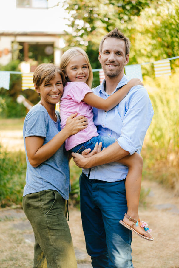 A happy family standing in front of their house, representing reliable AAA home insurance in Livonia, MI.