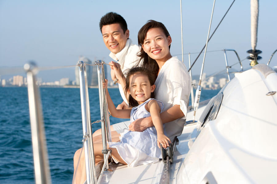 A happy family smiling together on a sailboat, representing comprehensive AAA boat insurance in Novi MI.