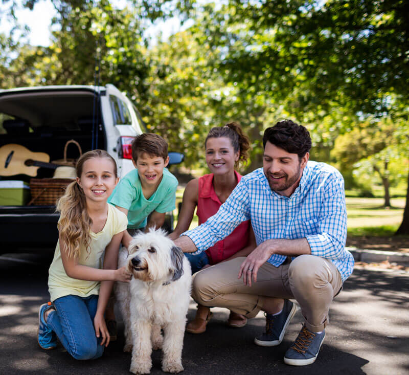 A happy family in Redford Charter Township gathered behind their SUV, protected by customized insurance policies from Mark Ismail Insurance Agency.