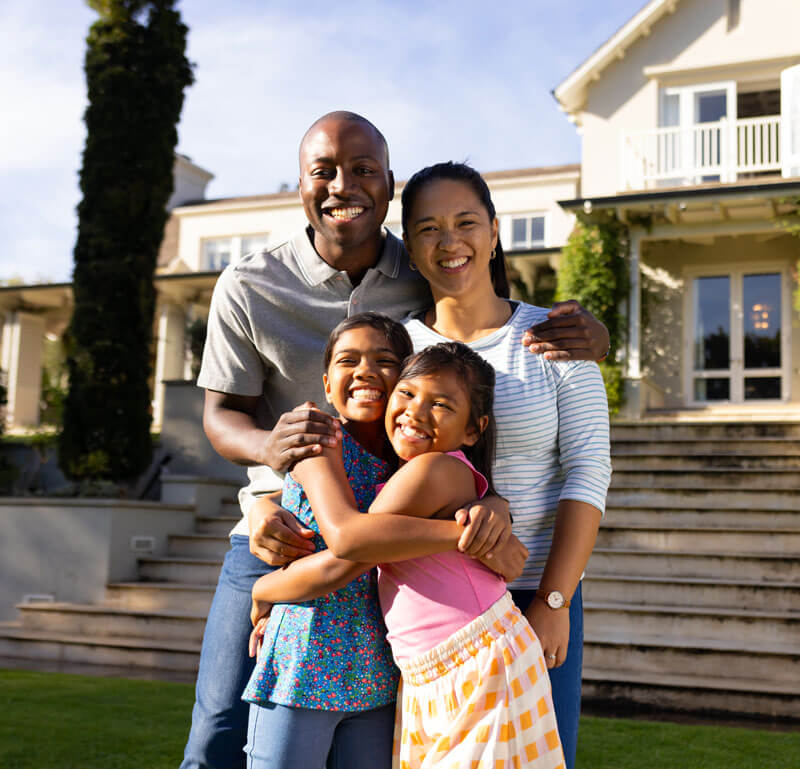 A happy family standing in front of their house, representing reliable AAA home insurance in Northville MI.